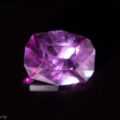 A close-up of the 0.88-Carat Blue-Violet Color Change Garnet against a dark background. The gemstone exhibits a brilliant sparkle due to the way it is cut. The bottom left corner contains a small, semi-transparent watermark reading "© Earth's Treasury.