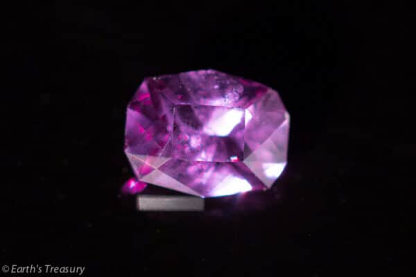 _56A8802-1024 A close-up of the 0.88-Carat Blue-Violet Color Change Garnet against a dark background. The gemstone exhibits a brilliant sparkle due to the way it is cut. The bottom left corner contains a small, semi-transparent watermark reading "© Earth's Treasury.
