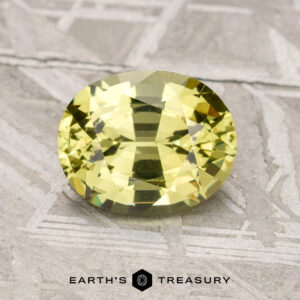 A faceted, oval-cut 1.78-carat Mali Garnet, placed on a textured gray surface, with the logo and text "Earth's Treasury" visible at the bottom.
