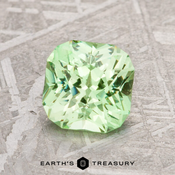 1.67-Carat Mint Green Grossular Garnet A 1.67-carat mint green grossular garnet with a square cut rests on a textured surface. Text below reads "Earth's Treasury.