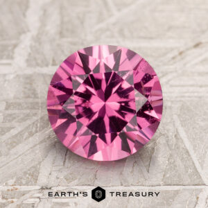 2.16-carat hot pink spinel with facets, resting on a textured surface.