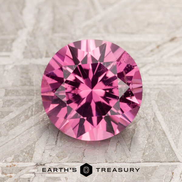 2.16-carat hot pink spinel with facets, resting on a textured surface.
