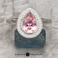 The "Grace" ring features a 1.40-carat pear-shaped pink tourmaline in 14K white gold with a diamond halo, displayed on a rough dark green stone.