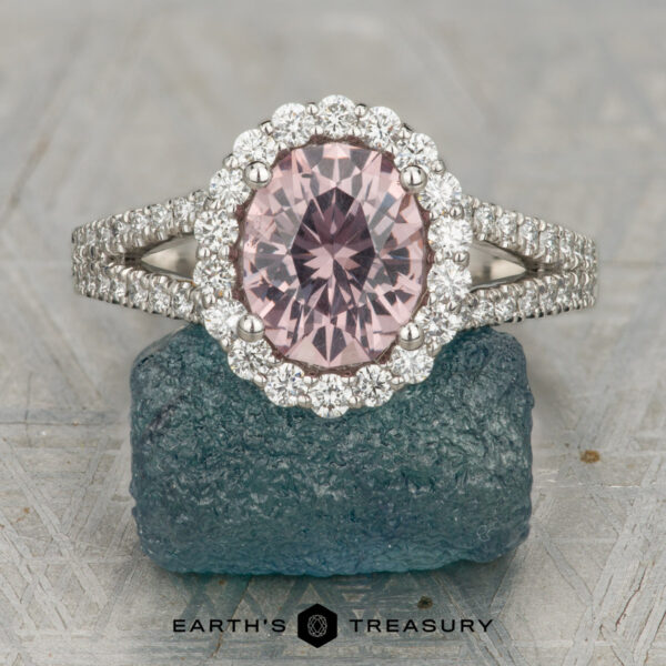 The "Charlotte" ring in platinum with 1.67-carat Mahenge garnet The "Charlotte" ring in platinum features a 1.67-carat round Mahenge garnet center stone, surrounded by clear accents, displayed on a textured blue stone base with the text "EARTH'S TREASURY" below.