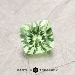 Introducing ET1108: A stunning square-cut green gemstone with precise facets, elegantly displayed on a textured gray surface.