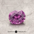 A faceted pink gemstone, product ET1128, rests on a textured gray surface labeled "Earth's Treasury.