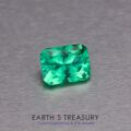 A vibrant 1.48-carat Ethiopian emerald, expertly cut in an emerald shape, is placed on a smooth, metallic surface. Below the gemstone, the text reads "EARTH'S TREASURY - Custom Gemstones & Fine Jewelry." The gemstone features clean, sharp facets and a brilliant, rich green color.
