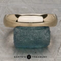 A Classic Band, Comfort Fit in 14K yellow gold (5.0mm wide), rests on a rough blue-green stone atop a textured gray surface with the "Earth's Treasury" logo below.
