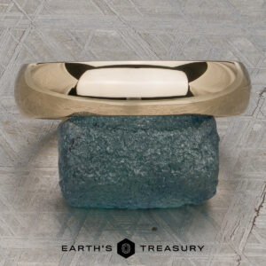 A Classic Band, Comfort Fit in 14K yellow gold (5.0mm wide), rests on a rough blue-green stone atop a textured gray surface with the "Earth's Treasury" logo below.