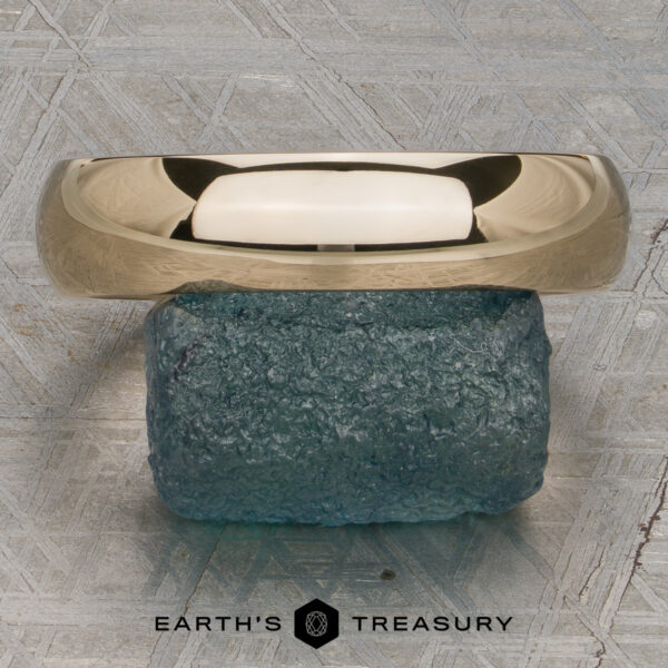 Classic Band, Comfort Fit in 14K yellow gold 5.0mm wide A Classic Band, Comfort Fit in 14K yellow gold (5.0mm wide), rests on a rough blue-green stone atop a textured gray surface with the "Earth's Treasury" logo below.