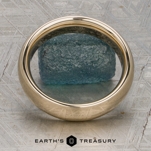 Classic Band, Comfort Fit in 14K yellow gold 5.0mm wide A Classic Band, Comfort Fit in 14K yellow gold (5.0mm wide), rests on a rough blue-green stone atop a textured gray surface with the "Earth's Treasury" logo below.