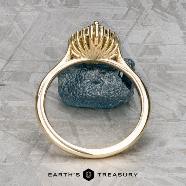 The "Anne" ring in 14k yellow gold with 1.44-carat Australian sapphire The "Anne" ring in 14k yellow gold with a 1.44-carat Australian sapphire stands upright on a rough gemstone, with the Earth’s Treasury logo shown below on a textured background.