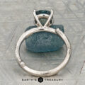 The "Twyg" ring in 14K white gold, featuring a 2.05-carat Montana sapphire, is displayed atop a rough blue stone with the text "Earth's Treasury" below.
