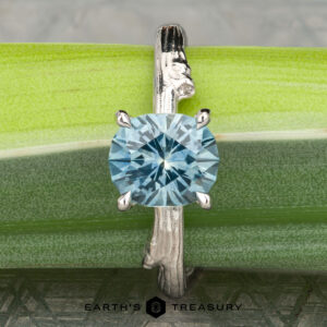 The "Twyg" ring in 14K white gold with a 2.05-carat Montana sapphire is shown upright on a green Twyg bamboo stalk, with the Earth's Treasury logo at the bottom of the image.