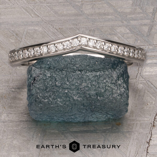 A platinum “Faye” band encircles a rough, dark green stone, displayed on a textured gray surface with the Earth’s Treasury logo at the bottom.