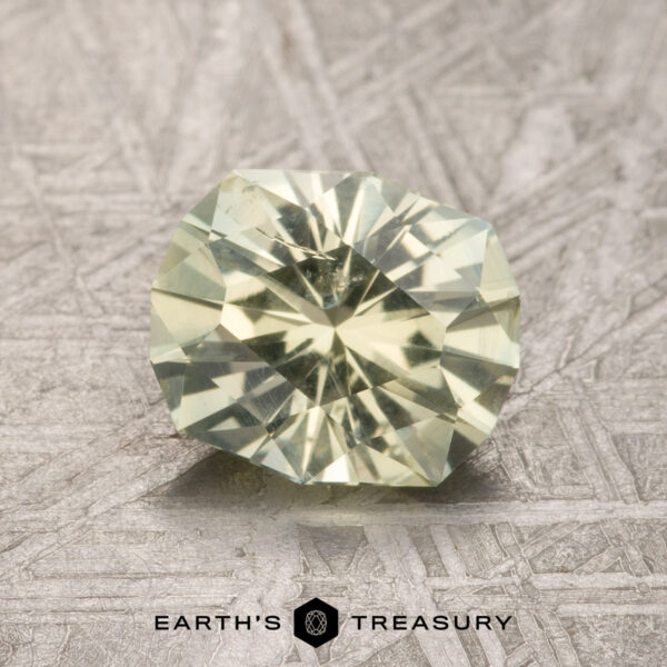 1.67-Carat Light Yellow Montana Sapphire A 1.67-carat Light Yellow Montana Sapphire, round and faceted, is shown on a textured gray surface with the "Earth's Treasury" logo below.