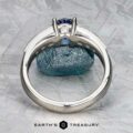 The Cascade ring in platinum with a 1.24-carat Ceylon sapphire is displayed upright against a blue rock on textured gray, with the "Earth's Treasury" logo at the bottom.