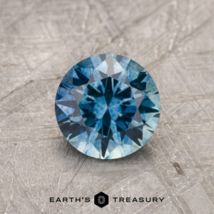 A blue-green Montana sapphire in a classic diamond round brilliant design