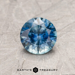 A blue-green Montana sapphire in a classic diamond round brilliant design
