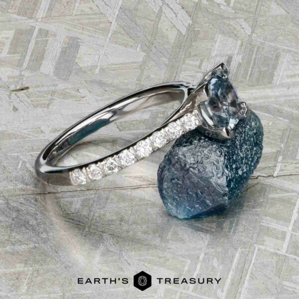 The "Meissa" ring in 14K white gold with 1.47-carat Montana sapphire The "Meissa" ring in 14K white gold with a 1.47-carat Montana sapphire and diamond accents rests on a rough blue stone, its beauty enhanced by the metallic background and the Earth’s Treasury logo below.