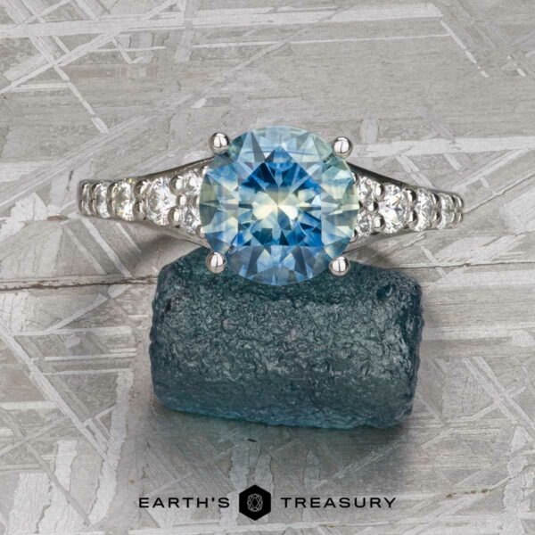 The "Arethusa" ring in platinum with 2.65-carat Montana sapphire The "Arethusa" ring features a 2.65-carat Montana sapphire set in platinum, shown on a textured blue mineral background with the "Earth's Treasury" logo below.