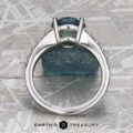 The "Arethusa" ring in platinum, featuring a 2.65-carat Montana sapphire, is displayed upright on a textured surface with the Earth's Treasury logo at the bottom.