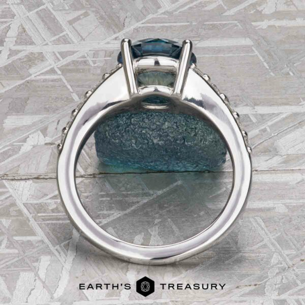 The "Arethusa" ring in platinum with 2.65-carat Montana sapphire The "Arethusa" ring in platinum, featuring a 2.65-carat Montana sapphire, is displayed upright on a textured surface with the Earth's Treasury logo at the bottom.