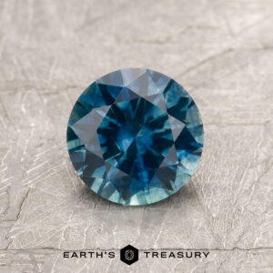 A blue-green Montana sapphire in a classic diamond round brilliant design