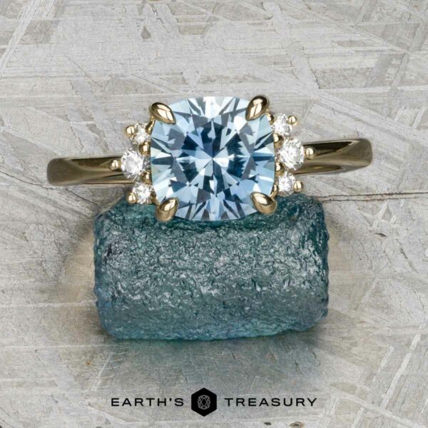 The "Hesperia" ring in 14K yellow gold with 2.21-carat Montana sapphire The "Hesperia" ring in 14K yellow gold features a 2.21-carat Montana sapphire and accent diamonds, displayed on rough blue mineral with "Earth's Treasury" text below.