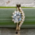 The "Hesperia" ring in 18K yellow gold with a 1.44-carat Montana sapphire is paired with the matching "Hesperia" band, both shown on a green surface.