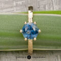 The "Snowflake" ring in 18K yellow gold, hammered and polished, featuring a 1.80-carat Montana sapphire, stands upright on a green leaf with the Earth's Treasury logo below—evoking the style of Snowflake Solitaire.