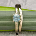 The "Snowflake" ring in 14K yellow gold, featuring a hammered finish and 1.06-carat Montana sapphire, is shown with the custom-fit contour band atop a green leaf, with "Earth's Treasury" text below.