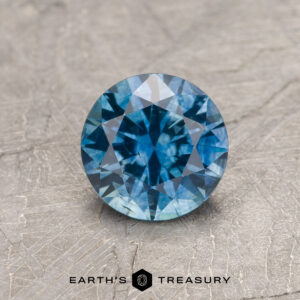 A blue-green Montana sapphire in a classic diamond round brilliant design