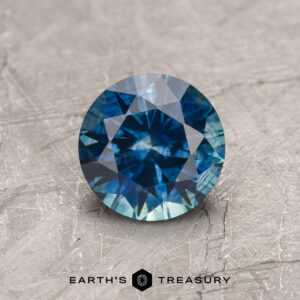 A blue-green Montana sapphire in a classic diamond round brilliant design