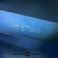 Close-up image of a 2.96-carat Royal Blue Madagascar Sapphire (Heated) engraved with "ET1818" under the logo "ET." At the bottom, the text "EARTH'S TREASURY" is displayed along with a geometric logo. The background appears to be a blurred blue gradient.