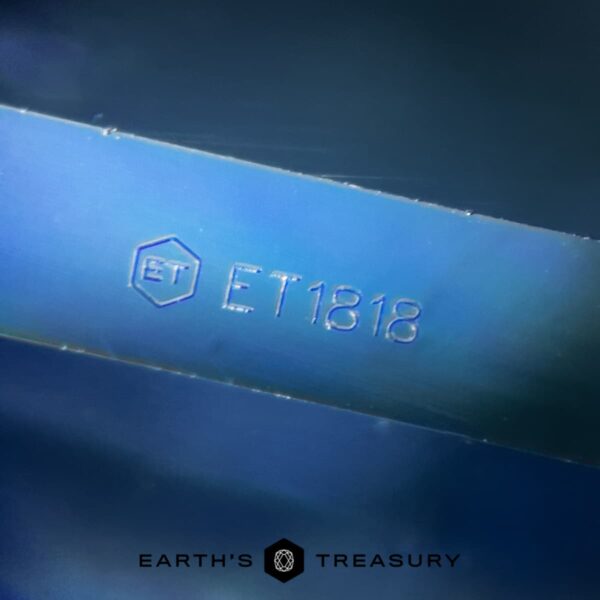 IMG_4084-1200-BW Close-up image of a 2.96-carat Royal Blue Madagascar Sapphire (Heated) engraved with "ET1818" under the logo "ET." At the bottom, the text "EARTH'S TREASURY" is displayed along with a geometric logo. The background appears to be a blurred blue gradient.