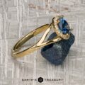 The "Diana" ring in 18K yellow gold with a 1.08-carat Montana sapphire, accented by small clear stones, is shown on a rough dark mineral with the Earth's Treasury logo at the bottom.