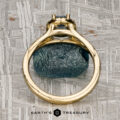 The "Diana" ring in 18K yellow gold with a 1.08-carat Montana sapphire is displayed on a metallic, patterned background featuring the "Earth's Treasury" logo at the bottom.