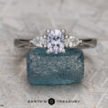 The "Clematis" ring in platinum, featuring a 0.74-carat rectangular Montana sapphire and two pear-shaped side stones, is displayed upright on rough blue crystal with the Earth's Treasury logo below, elegantly highlighting each gem.