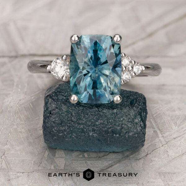 The "Erythia" ring in 14K white gold with 3.29-carat Montana sapphire The "Erythia" ring in 14K white gold features a 3.29-carat Montana sapphire framed by sparkling diamonds, resting on a rough blue stone. The text "EARTH'S TREASURY" appears below, capturing the enchanting allure of Erythia.