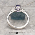 The "Clematis" Ring in platinum features a 1.62-carat Madagascar sapphire and an intricate prong setting, displayed upright on a gray textured surface with Earth’s Treasury logo below.