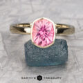 A 14K yellow gold Stackable "Emma" ring with a 2.02-carat California Tourmaline is displayed standing on a rough blue-green stone, with the Earth's Treasury logo visible below.
