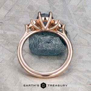 The "Liriope" ring in 14k rose gold features a 1.40-carat Montana sapphire, elegantly set atop a rough blue stone and displayed with the Earth's Treasury logo below.