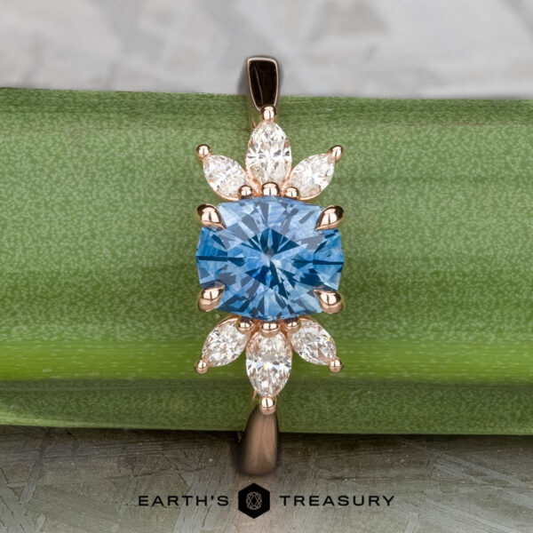 The "Liriope" ring in 14k rose gold with 1.40-carat Montana sapphire Showcasing the "Liriope" ring in 14k rose gold, this piece features a 1.40-carat Montana sapphire at its center with marquise and pear-shaped clear stones, elegantly displayed on a green background.