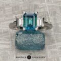 The "Cyanea" ring in 18K white gold features a 2.69-carat Montana Sapphire flanked by two clear stones, displayed on a rough blue crystal with the Earth's Treasury logo below.