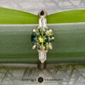 The "Mandevilla" ring in 14k yellow gold, featuring a 1.80-carat Australian sapphire and two rectangular side stones, is shown vertically on a lush green leaf. "EARTH'S TREASURY" appears at the bottom.