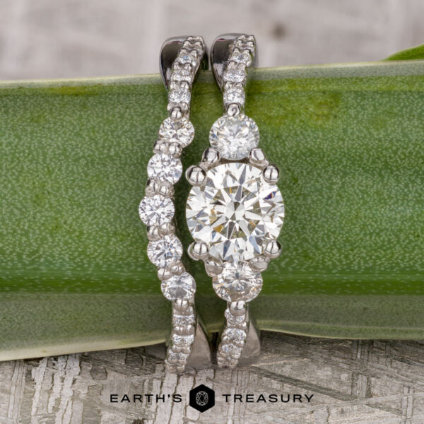 The "Lonicera" ring in platinum with 0.73-carat diamond, alongside the "Lonicera" band in platinum The "Lonicera" ring in platinum with a 0.73-carat diamond and the matching "Lonicera" platinum band are displayed upright on a green leaf, with the Earth's Treasury logo below.