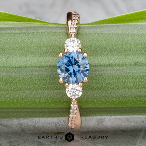 The "Lonicera" ring in 14k rose gold with 0.93-carat Montana sapphire The "Lonicera" ring in 14k rose gold features a 0.93-carat Montana sapphire at its center, accented by two sparkling side stones—where nature’s elegance meets fine jewelry.