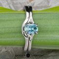The "Cybele" ring in 18K white gold with a 0.96-carat Montana sapphire and its custom-fit contour band rest on a green leaf, with the "Earth's Treasury" logo at the bottom.