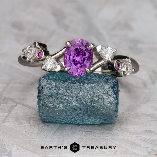 The "Jasmine" ring in platinum with 1.03-carat Madagascar sapphire The "Jasmine" ring in platinum, featuring a 1.03-carat Madagascar sapphire, is displayed on a rough blue crystal with the "Earth's Treasury" logo below.